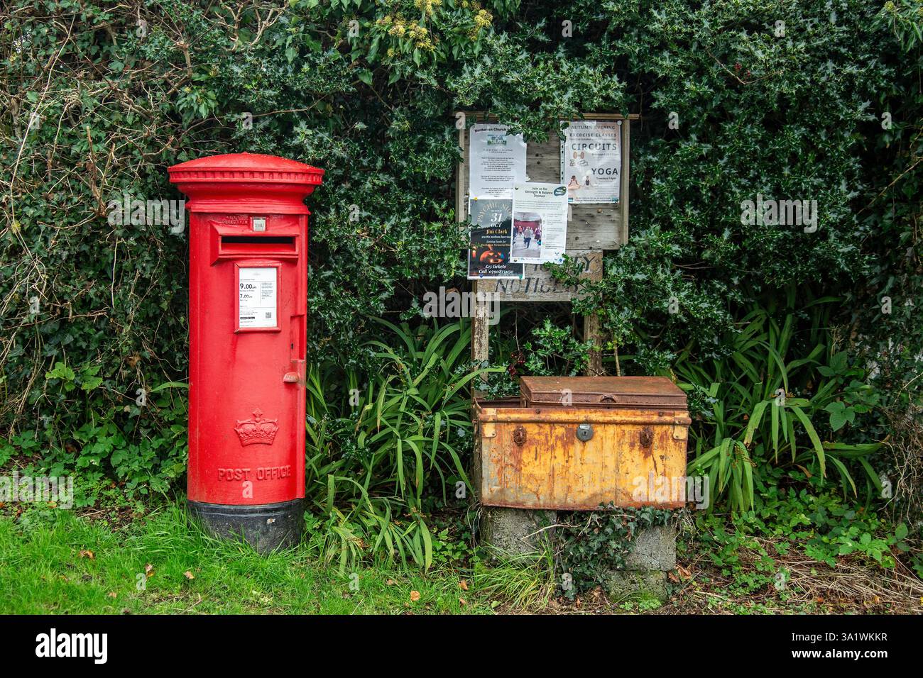 Ein knallroter Briefkasten der britischen Post, ein Schild der Gemeinde und ein rostender, orangener Paketversand in Balmaha am Ufer des Loch Lomond in Schottland Stockfoto