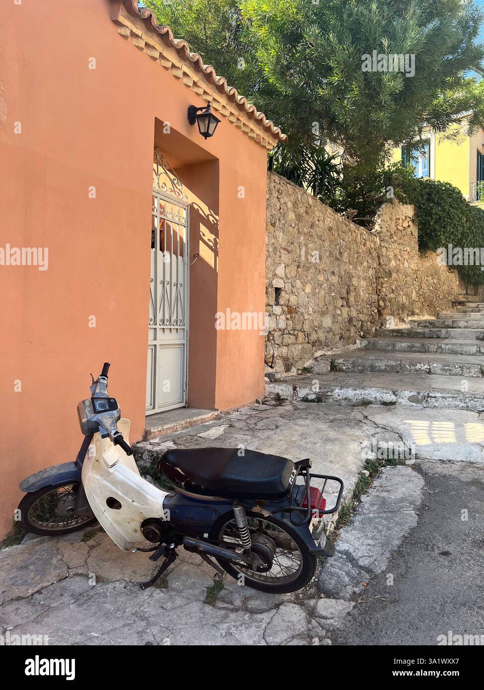 Ein alter Roller lehnt sich an ein Terrakotta-Haus in einer charmanten Gasse - Smartphone-aufgenommenes Stockfoto