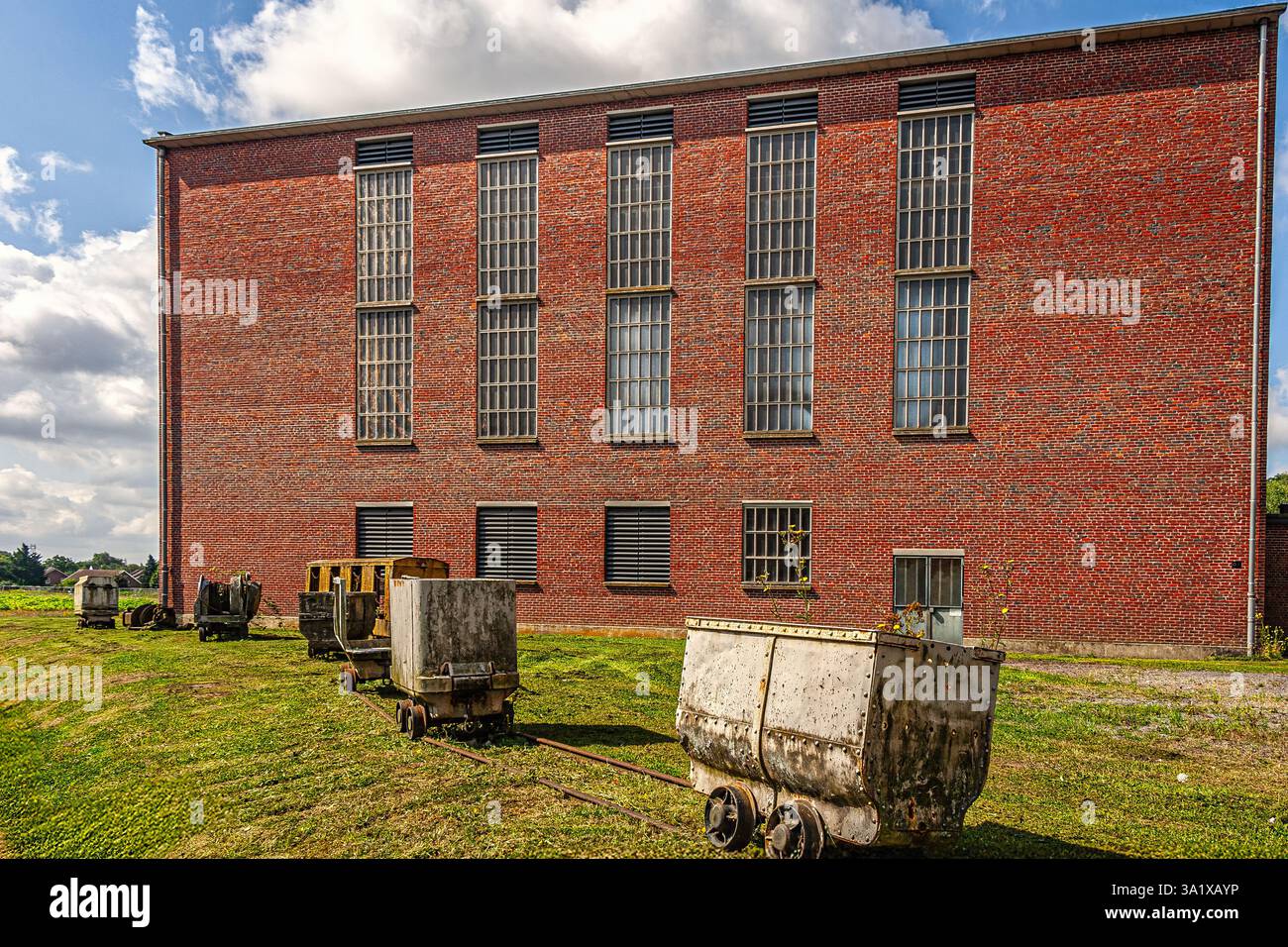 Rote Backsteinhäuser mit blauen Fensterläden am Arenberg-Bergbaugelände unter blauem, bewölktem Himmel. Nord-Pas-de-Calais, Wallers, Frankreich, Europa Stockfoto