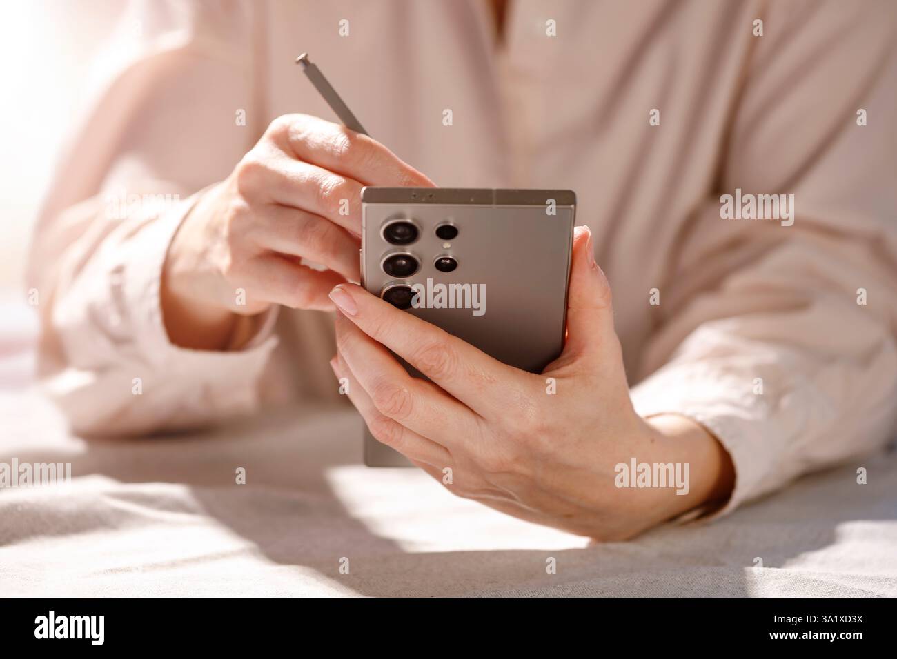 Frau, die einen Stift in der Hand hält, mit einem leeren Smartphone-Bildschirm. Stockfoto
