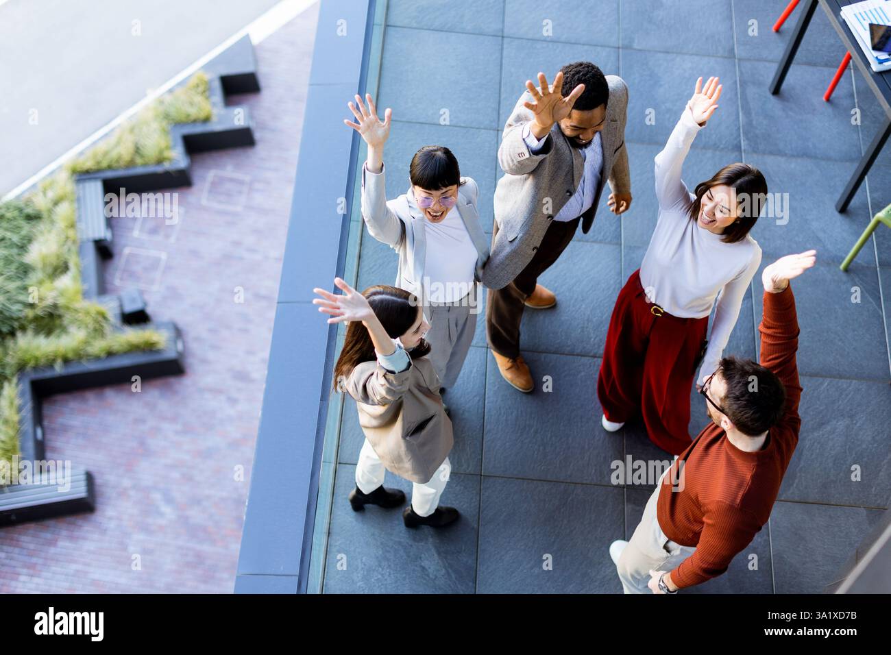 Ein lebhaftes Treffen von fünf Personen feiert Kameradschaft und Teamarbeit und genießt die Gesellschaft des anderen unter freiem Himmel an einem modernen Outdoor-Ort Stockfoto