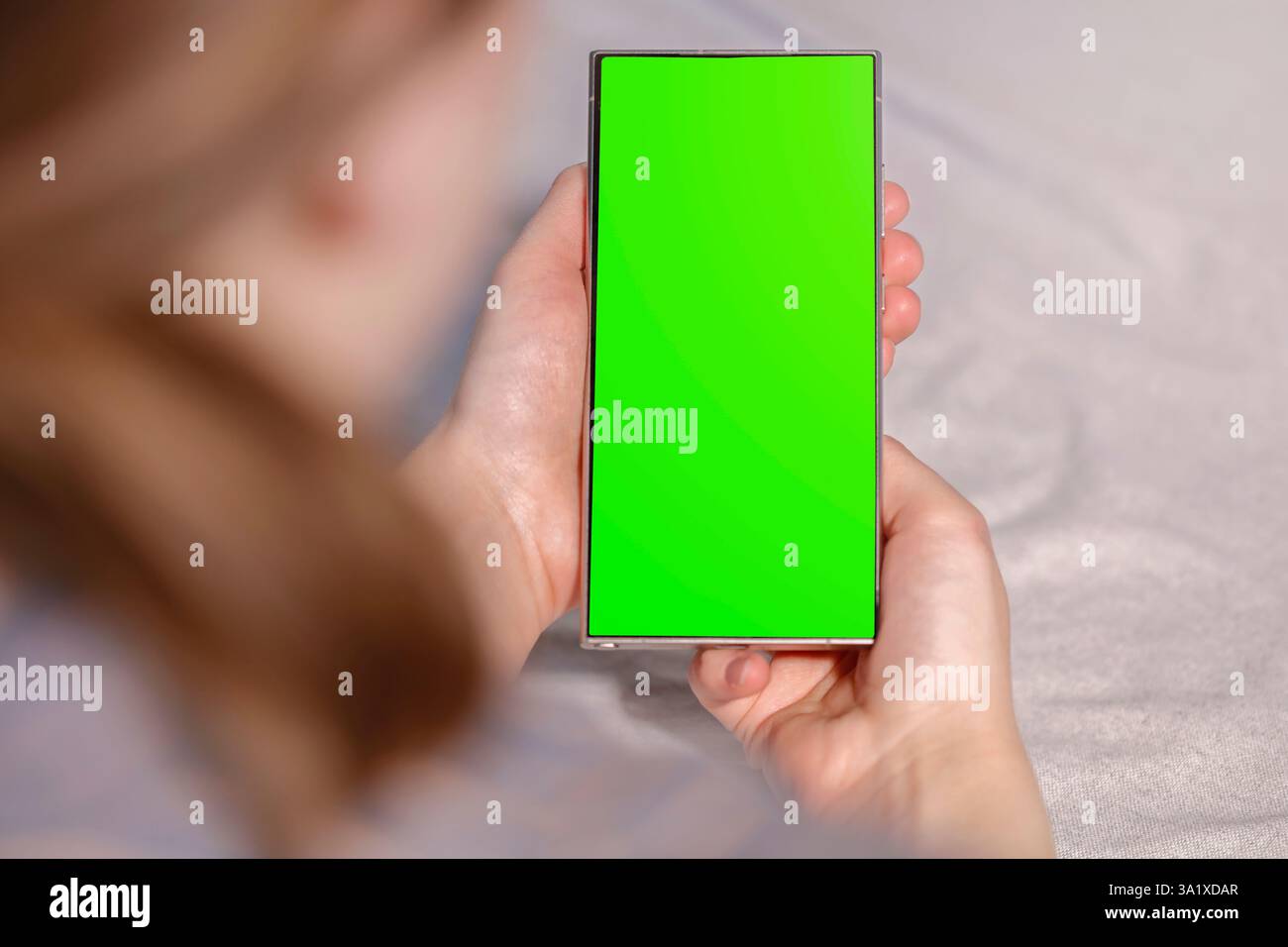 Frau im pfirsichfarbenen Hemd, die am Tisch sitzt und das Handy hält. Kopierbereich für Text und Produkt. Stockfoto