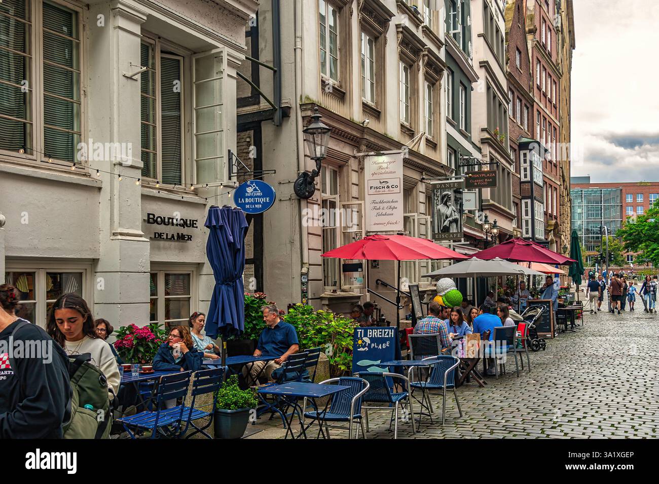 Touristen, die an einem sonnigen Nachmittag in den Cafés im Freien in einer charmanten Straße in Hamburg essen und trinken. Hamburg, Deutschland, Europa Stockfoto