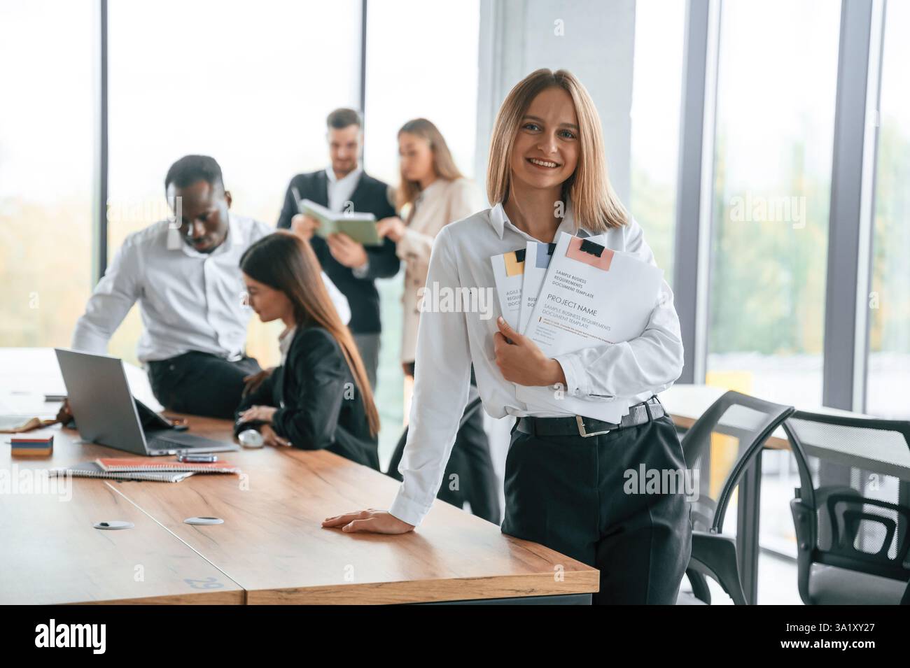 Porträt der glücklichen blonden Frau. Eine Gruppe von Büroangestellten ist drinnen zusammen. Stockfoto