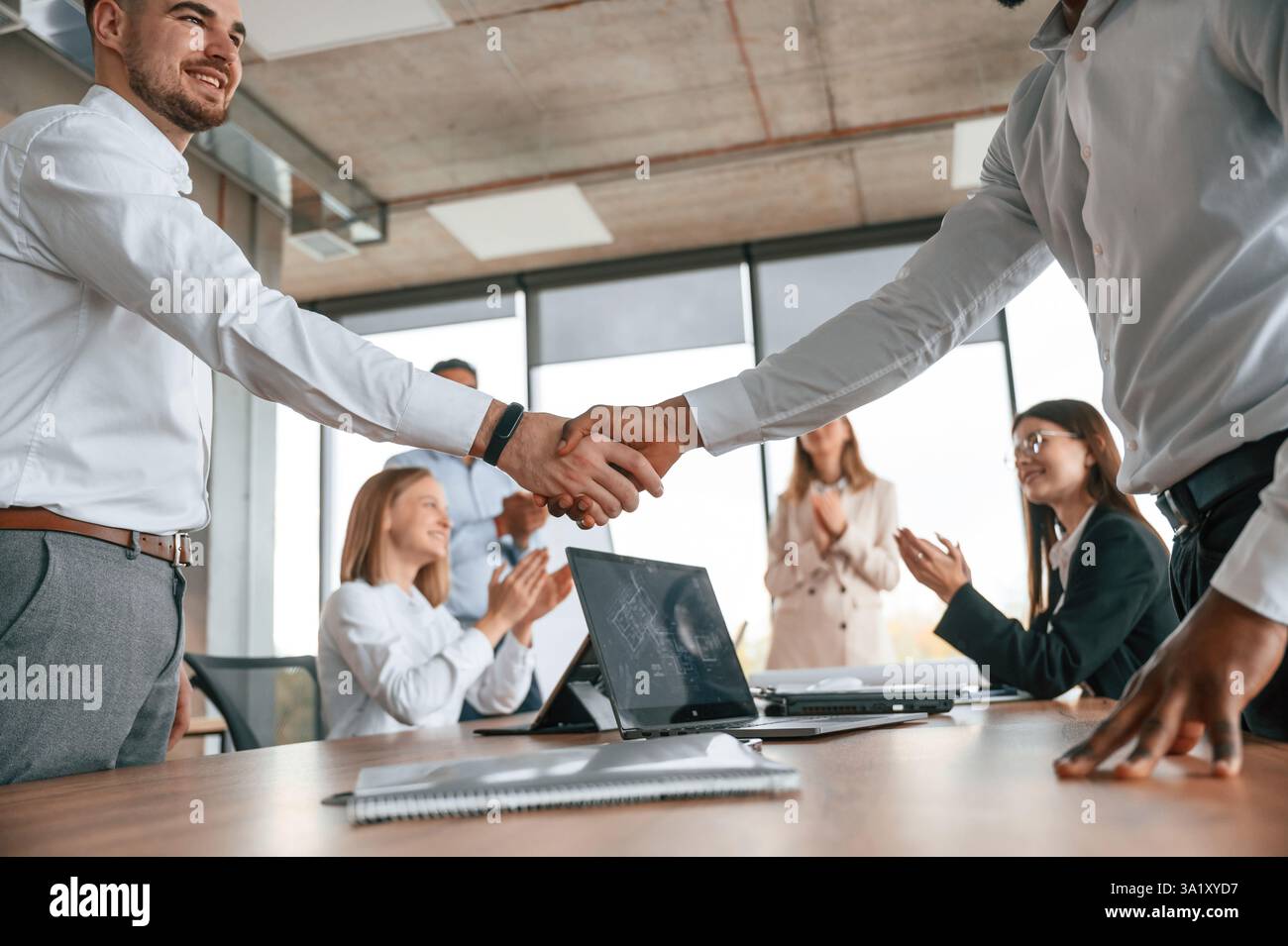 Nahaufnahme des Handshake. Erfolgreicher Deal. Eine Gruppe von Büroangestellten ist drinnen zusammen. Stockfoto