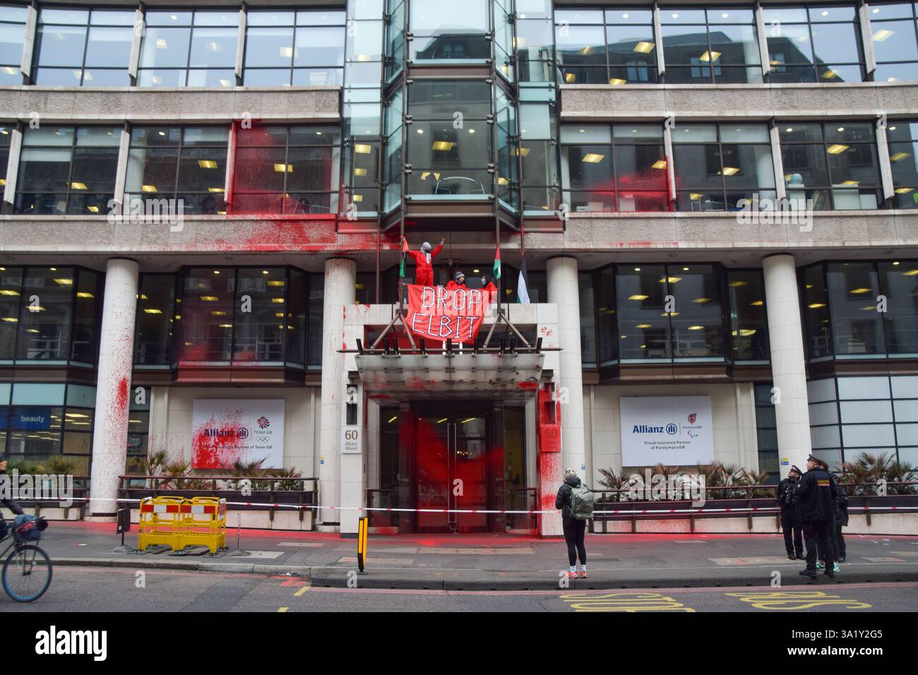 London, Großbritannien. März 2025. Aktivisten der Gruppe Palestine Action klettern auf den Eingang der Allianz-Büros in der City of London, nachdem sie das Gebäude mit roter Farbe besprüht haben. Die Aktivisten rufen den Versicherungsriesen auf, Verbindungen zum Waffenunternehmen Elbit Systems zu unterbrechen. Quelle: Vuk Valcic/Alamy Live News Stockfoto