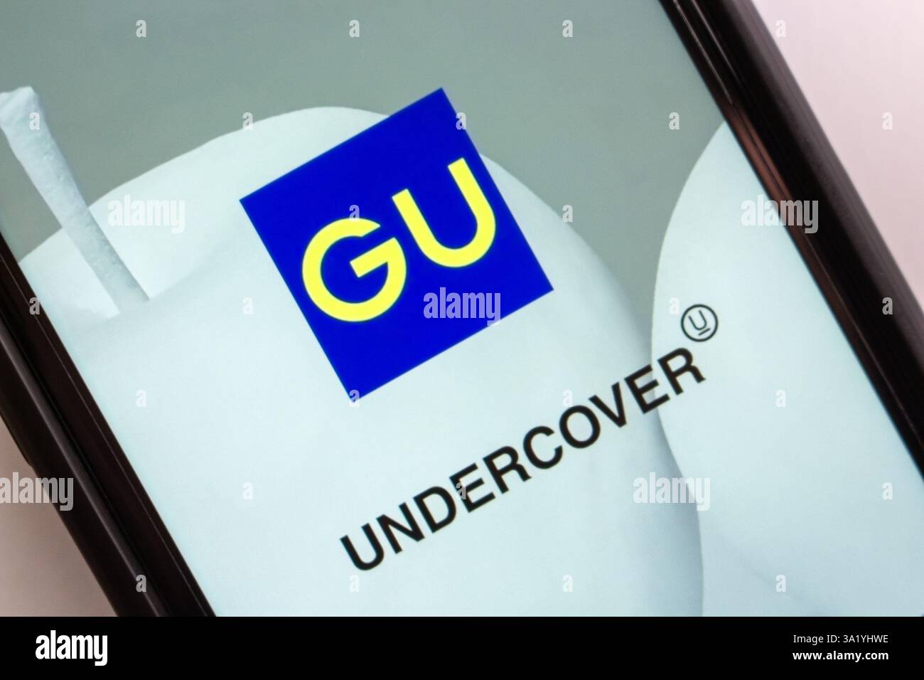 Ein Smartphone-Bildschirm mit GU und Undercover-Logo, auf dem die Partnerschaft und die neu eingeführte Modelinie UG dargestellt werden. Stockfoto