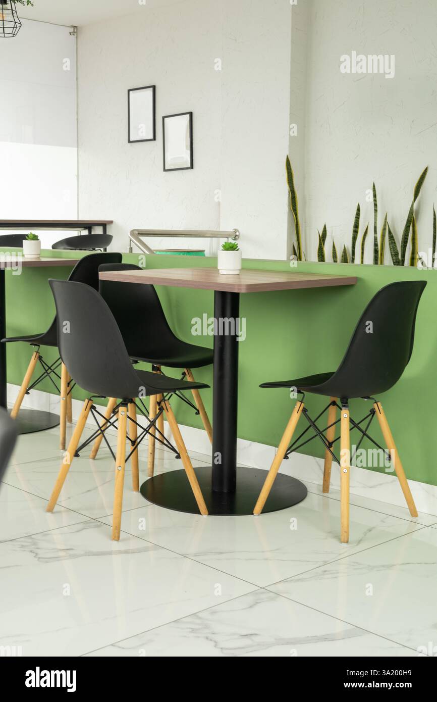 Ein modernes Bürocafé mit schwarzen Stühlen und kaffeefarbenen Tischen bietet einen stilvollen und komfortablen Raum für Arbeit und Entspannung. Stockfoto