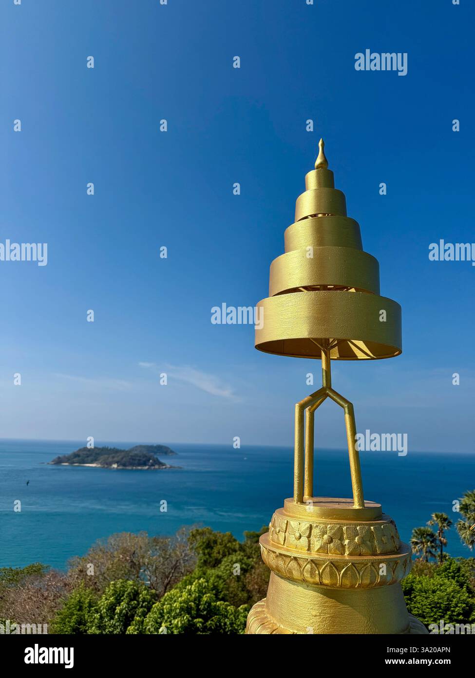 Goldene Spiralpagode mit Blick auf das Meer Eine goldene spiralförmige Pagode steht vor einem tiefblauen Himmel mit Panoramablick auf das Meer im Hintergrund. A - Smartphone-aufgenommenes Stockfoto