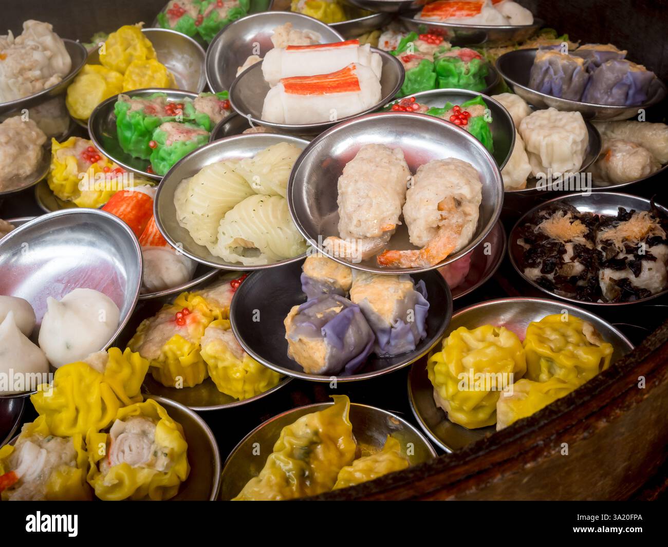 Verschiedene traditionelle Gerichte chinesisches Dim Sum in Minischüsseln im Dampfgarer, zubereitet in einem lokalen Restaurant. Nahaufnahme chinesisches Dim Sum Take-away Fingerfood. Lecker Stockfoto