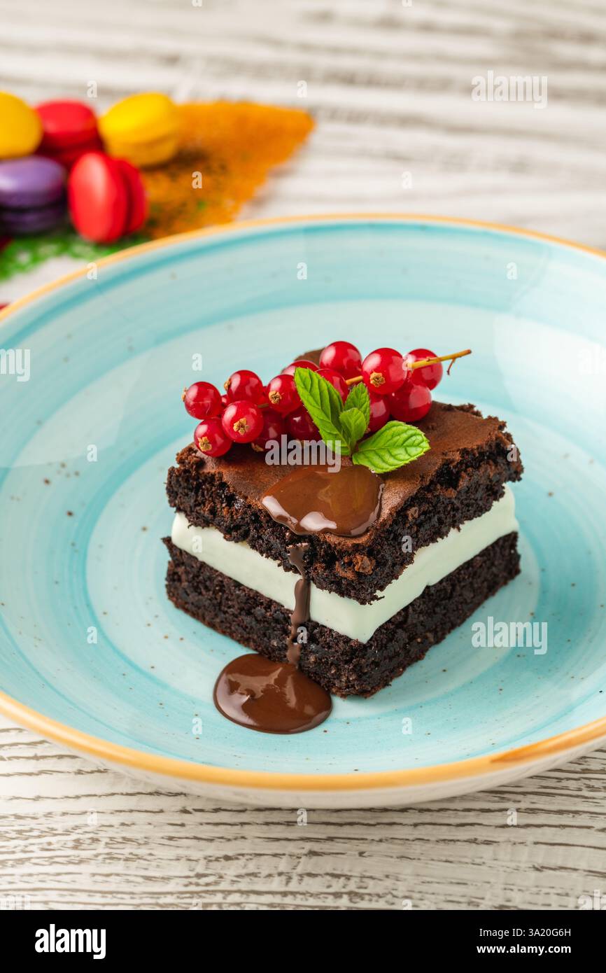 Schokoladenminz-Brownie mit Sahnefüllung, Schokoladensauce und Beeren Stockfoto