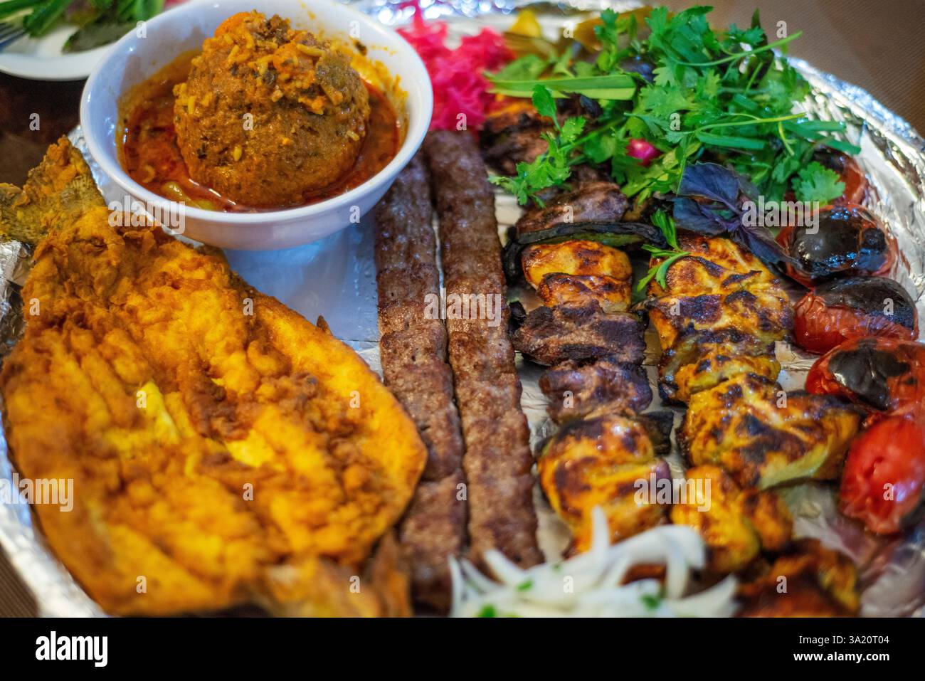 Typisch iranisches Essen: Hammel- und Hühnerspieße, Fisch, Tomaten, Suppe und khoresh Bademjan-Fleisch und Auberginen-Eintopf, - Teheran, Iran Stockfoto