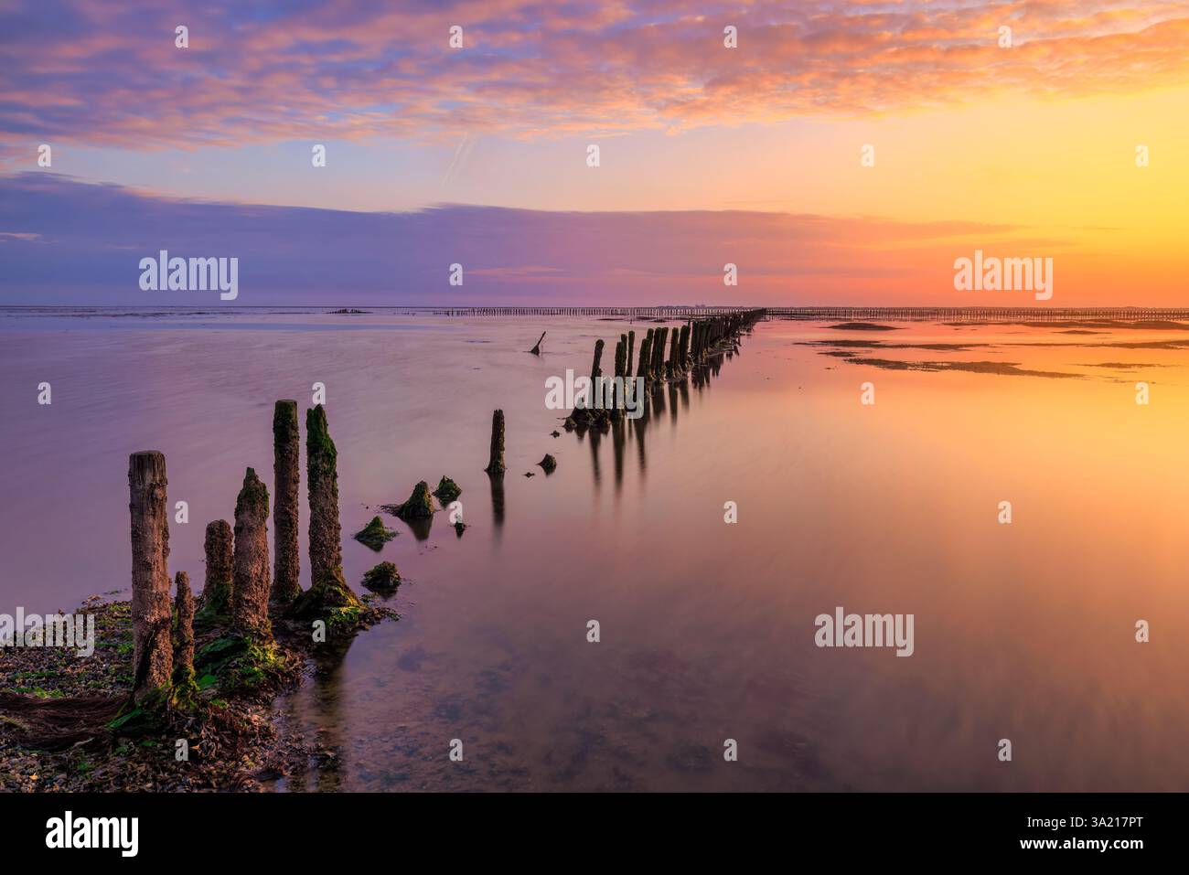 Ein wunderschöner Sonnenuntergang über dem Wattenmeer mit einem Himmel voller Abendrot. Die Farben spiegeln sich auf dem Wasser des Meeres wider. - Meeresbild Stockfoto