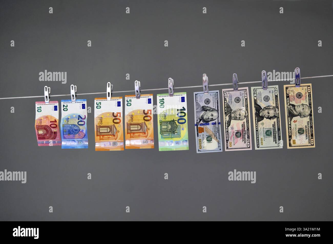 10-, 20-, 50-, 100-Euro-Banknoten und 100-, 10-Dollar-Banknoten, die mit Clips an einer Wäscheleine hängen Stockfoto