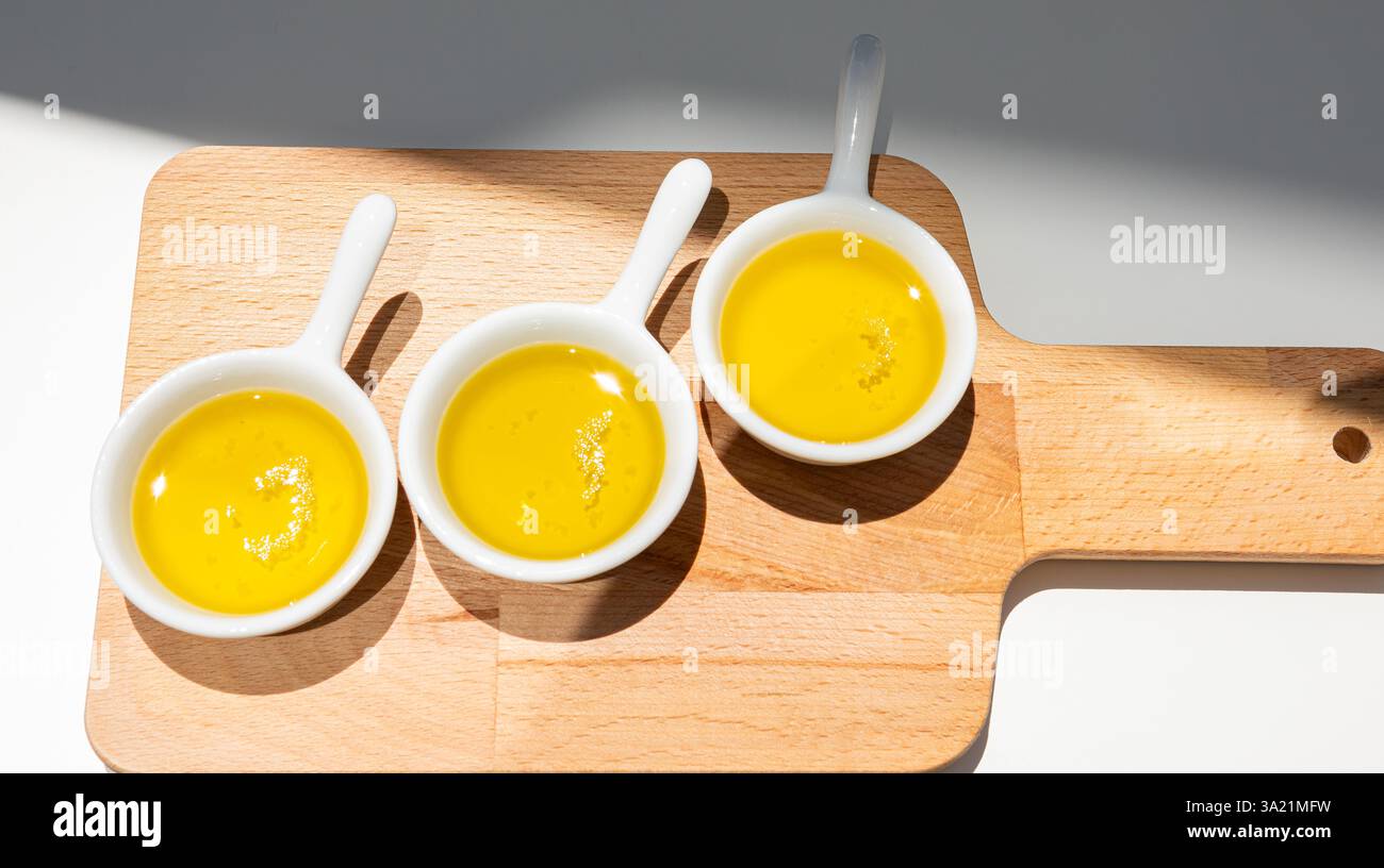Drei Sorten portugiesisches Olivenöl, serviert auf einem kleinen Holzbrett Stockfoto