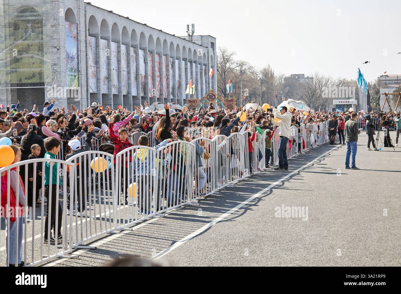 Eine Menschenmenge steht hinter einem Zaun in der Nähe einer festlichen Konzertbühne. Ala-Too Stadtplatz. Nooruz Feiertagsfeier. Bischkek, Kirgisistan - 21. März 2023 Stockfoto