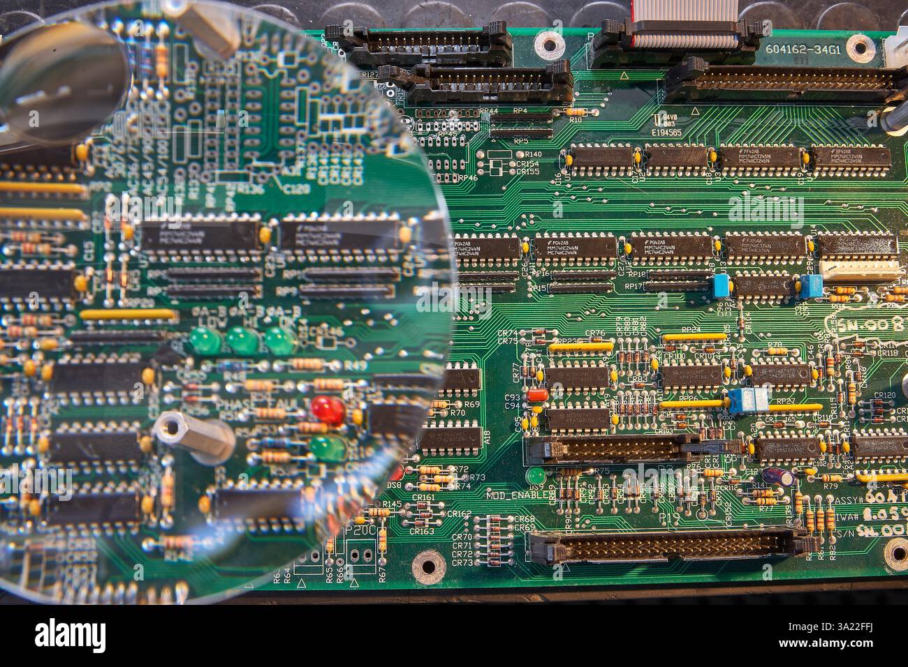 Nahaufnahme einer elektronischen Leiterplatte durch ein Vergrößerungsglas Stockfoto