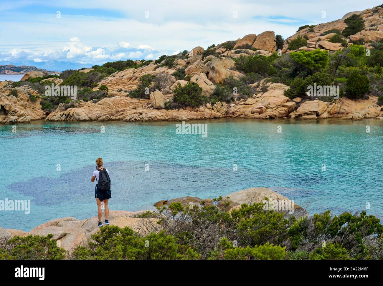 Eine Touristenfrau, die vor dem azurblauen Wasser der Insel Caprera, Sardinien, Italien, steht Stockfoto