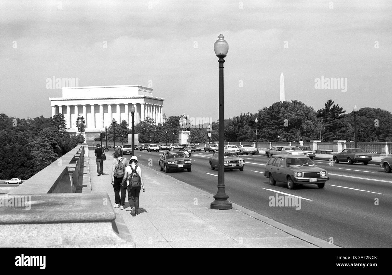Arlington Bridge mit historischem Blick auf das Lincoln Memorial. Amerikanische Autos, die Anfang der 80er Jahre produziert wurden, überqueren die Brücke und drei Fußgänger laufen auf dem Bürgersteig. Washington Monument im Hintergrund. Schwarzweiß-Fotografie, aufgenommen im Mai 1984 auf ORWO Negativfilm. Stockfoto Arlington Bridge mit historischem Blick auf das Lincoln Memorial. Amerikanische Autos, die Anfang der 80er Jahre produziert wurden, überqueren die Brücke und drei Fußgänger laufen auf dem Bürgersteig. Washington Monument im Hintergrund. Schwarzweiß-Fotografie, aufgenommen im Mai 1984 auf ORWO Negativfilm. Stockfoto