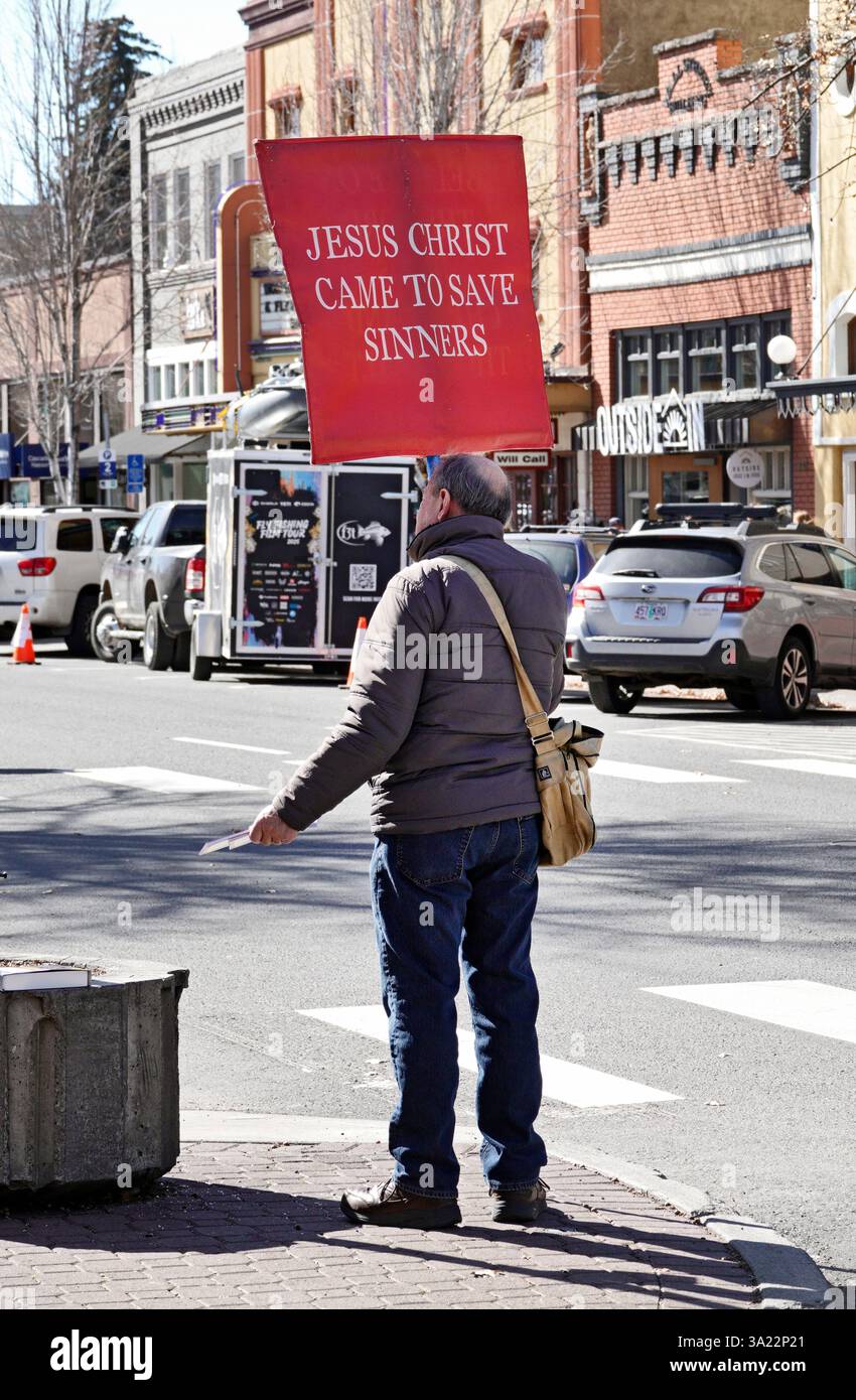 Ein Mann mittleren Alters, der auf einer Stadtstraße in Bend, Oregon, proselytisiert, während er Passanten religiöse Literatur verrät. Stockfoto
