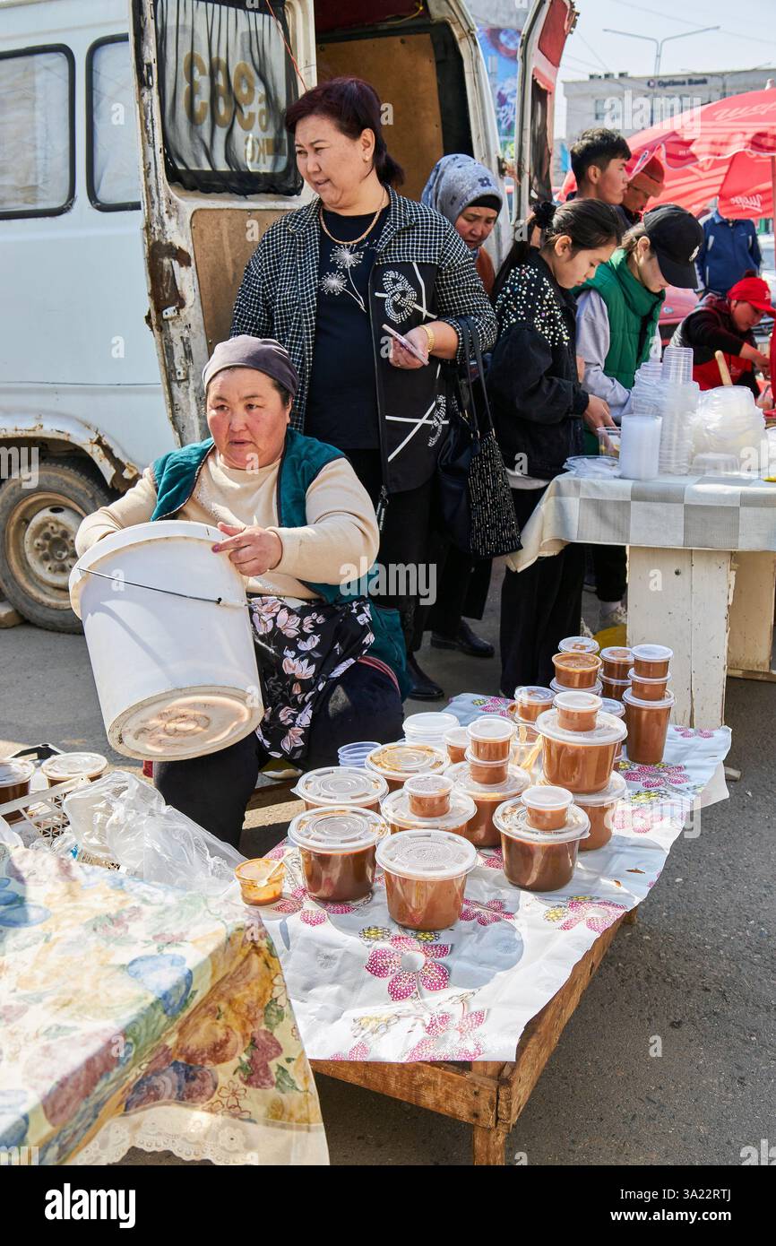 Straßenverkäufer verkaufen festliche Tafelsumalak in Plastikbehältern, Nowruz-Feier. Bischkek, Kirgisistan - 21. März 2023 Stockfoto