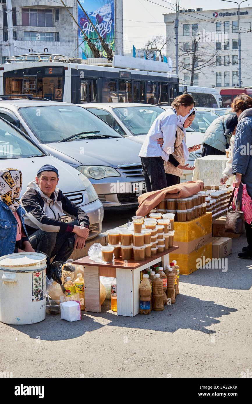 Straßenverkäufer verkaufen festliche Tafelsumalak in Plastikbehältern, Nowruz-Feier. Bischkek, Kirgisistan - 21. März 2023 Stockfoto