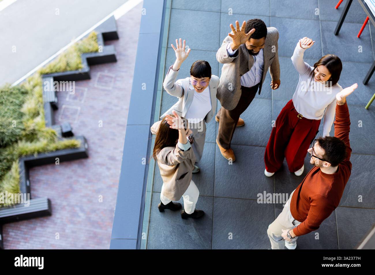 Ein lebhaftes Treffen von fünf Personen feiert Kameradschaft und Teamarbeit und genießt die Gesellschaft des anderen unter freiem Himmel an einem modernen Outdoor-Ort Stockfoto
