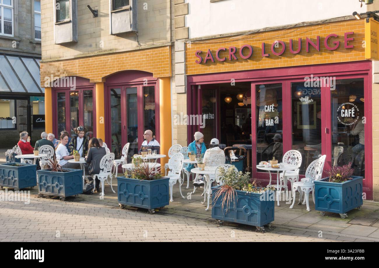 Die Leute saßen vor dem Sacro Lounge Café im Stadtzentrum von Buxton, Derbyshire, England, Großbritannien Stockfoto