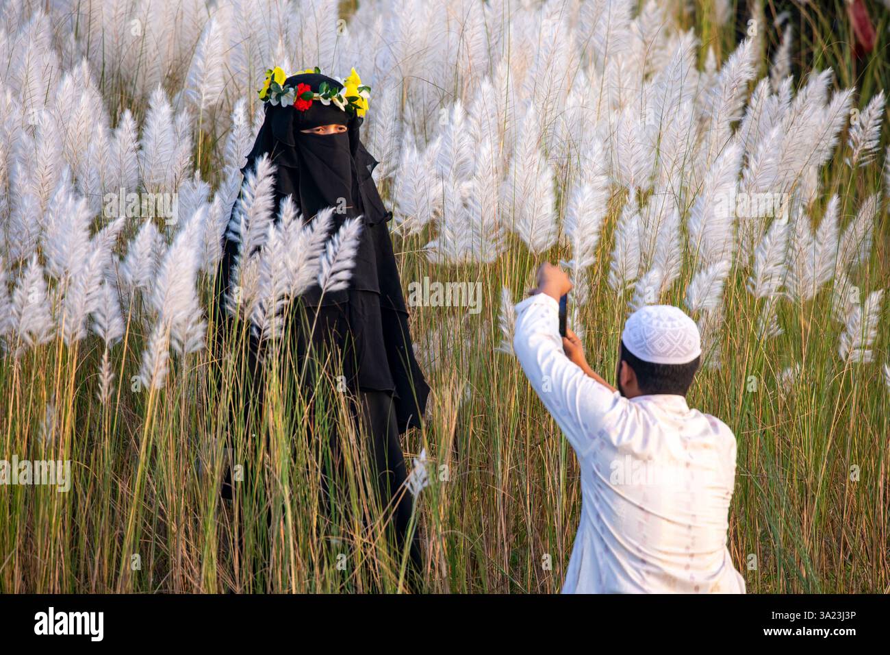 Ein muslimisches Paar, das in die Schönheit der blühenden Kans-Grasblumen eintaucht und das Wesen des Herbstes am Stadtrand von Dhaka, Bangla, feiert Stockfoto