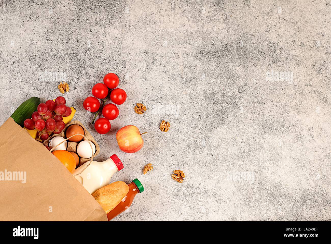 Papiertüte mit verschiedenen Naturprodukten. Milch, Eier, Baguettes, Natursaft, Gemüse und Obst in einem Druckverschlussbeutel auf Betonhintergrund, Lebensmittel d Stockfoto