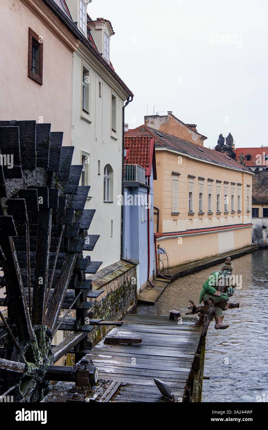 21.02.2025, Prag, altes Wasserrad und eine Statue eines Kabouter, einer mythischen Kreatur aus der europäischen Folklore, dekoriert den Čertovka-Kanal in Prag, C. Stockfoto