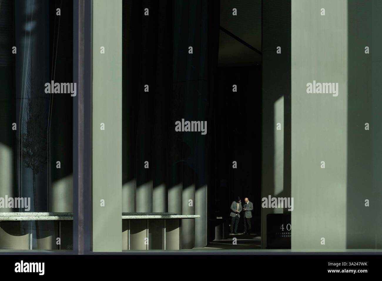 Zwei Figuren im Foyer eines modernen Bürogebäudes mit Licht und Schatten, City of London, Großbritannien Stockfoto Zwei Figuren im Foyer eines modernen Bürogebäudes mit Licht und Schatten, City of London, Großbritannien Stockfoto