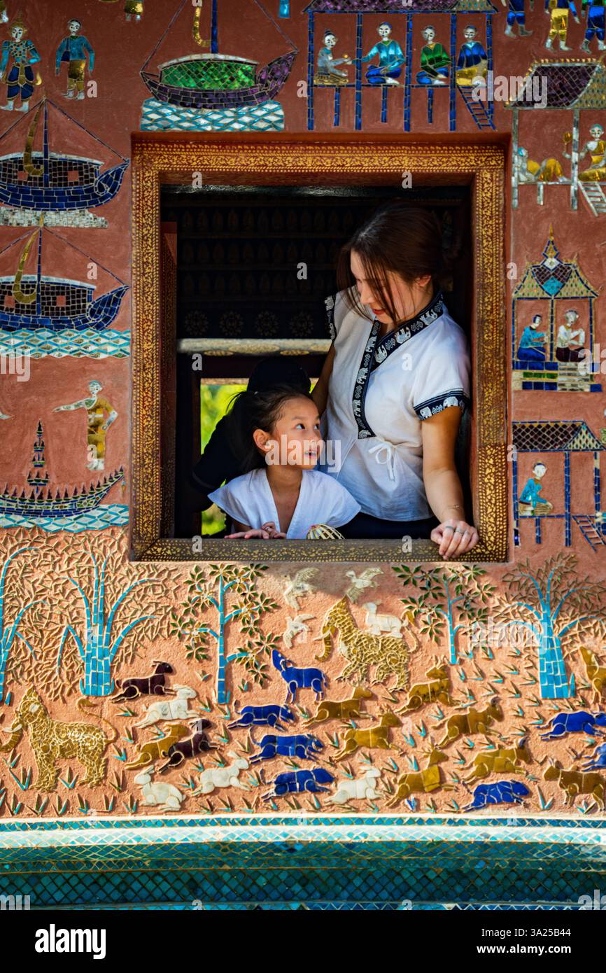 Mutter und Kind im Wat Xieng Thong, Luang Prabang, Laos. Traditionelle Kunst, Kulturfenster Stockfoto