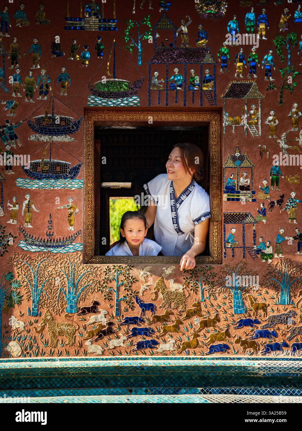 Mutter und Kind im Wat Xieng Thong, Luang Prabang, Laos. Traditionelle Kunst, Kulturfenster Stockfoto