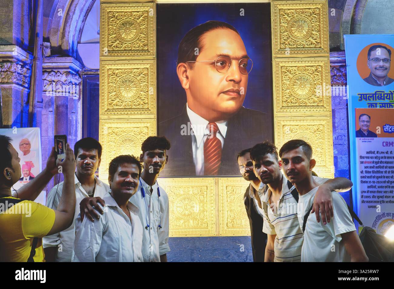 Am Todestag von B.R. Ambedkar, Gründer einer neo-buddhistischen Bewegung, posiert eine Gruppe von Männern aus Mumbai, Indien, vor seinem riesigen Porträt Stockfoto