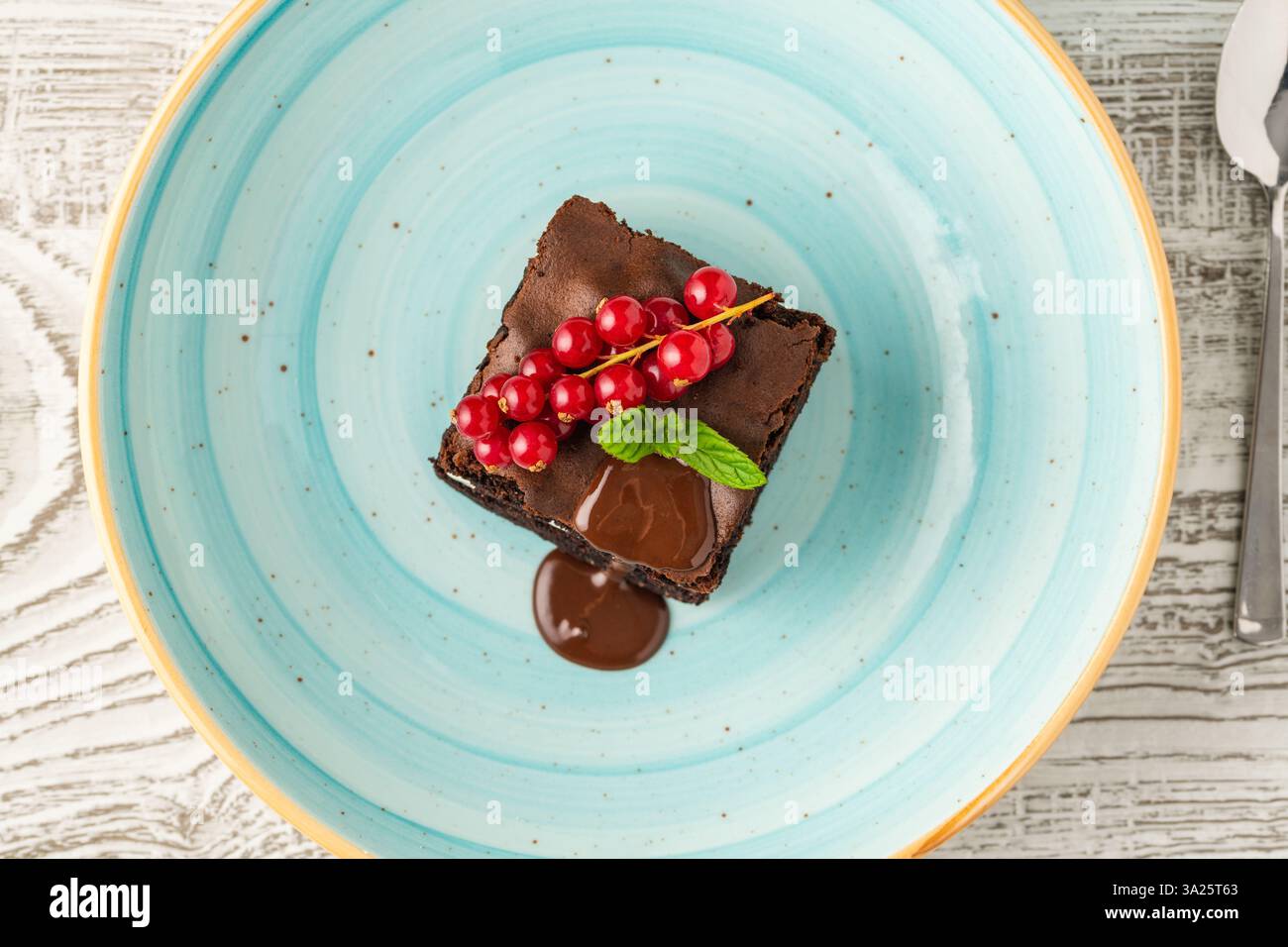Schokoladenminz-Brownie mit Sahnefüllung, Schokoladensauce und Beeren Stockfoto