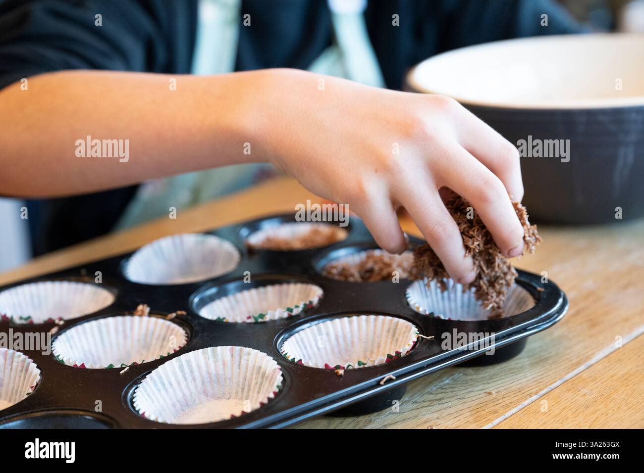 Die Hand des Jungen, die Kuchenmischung in das Tablett in der Küche gelegt hat. Stockfoto
