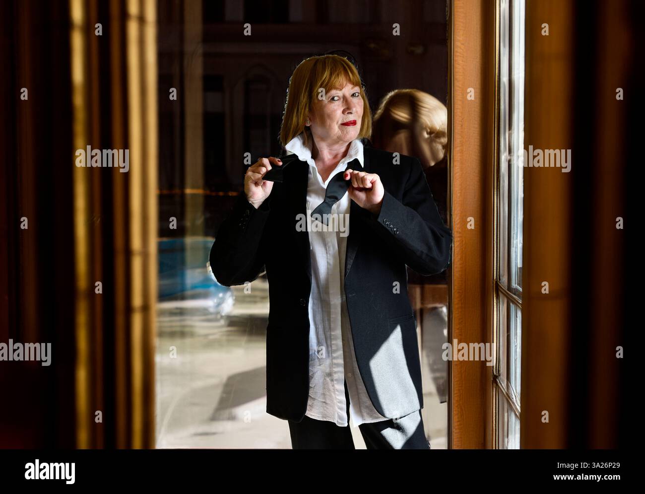 Dame mit schwarzem Krawattenanzug, der sich auf eine Party vorbereitet Stockfoto