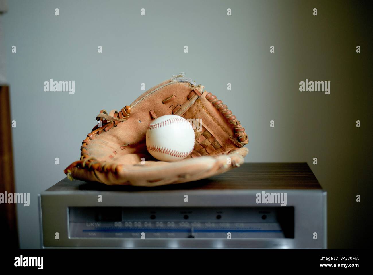 Ein Baseballhandschuh, der einen Baseball hält, liegt auf einem elektronischen Gerät in Vilnius, Litauen Stockfoto