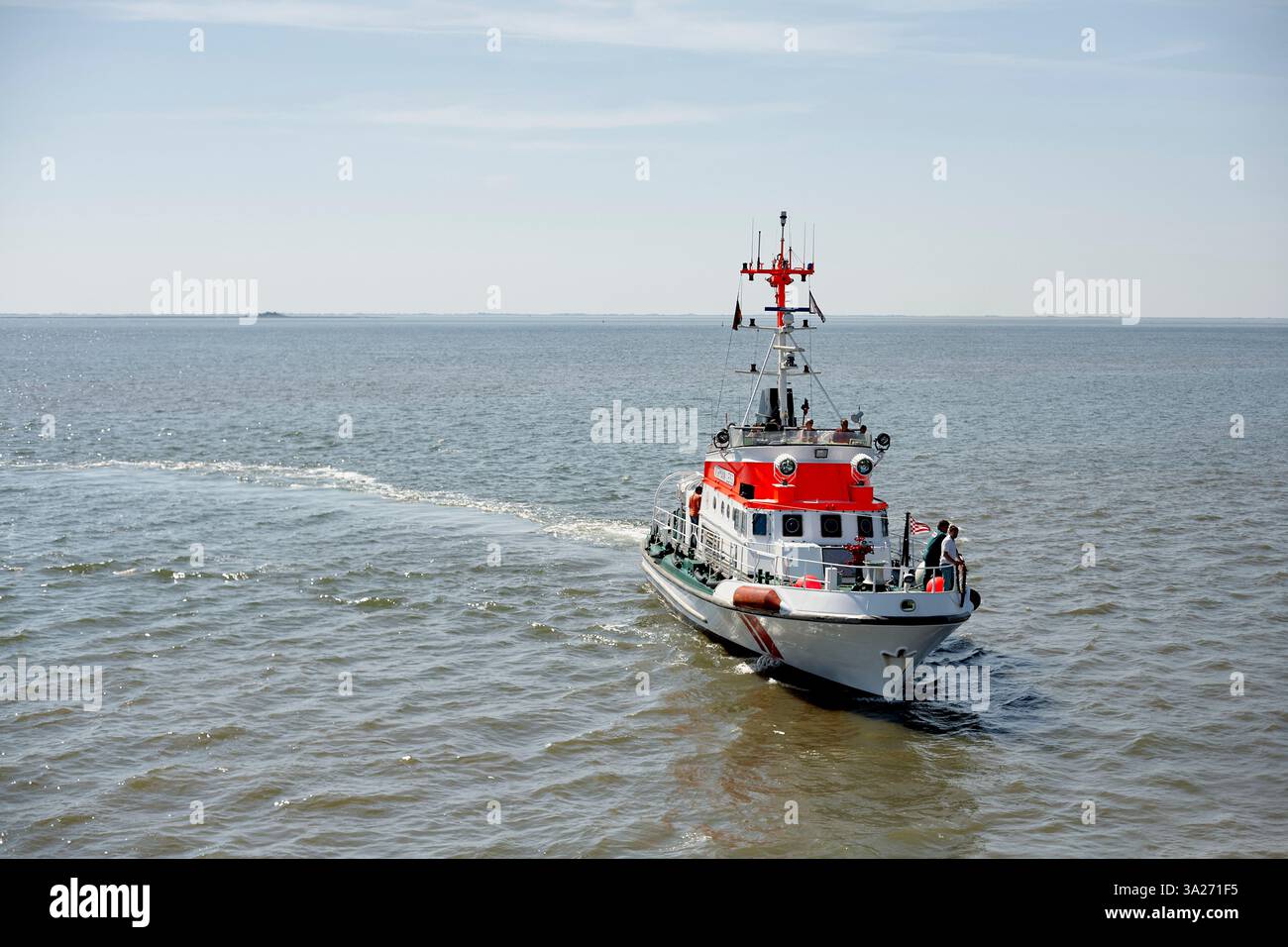 Rot-weißes Rettungsboot segelt auf einer ruhigen See unter einem klaren blauen Himmel. Nordsee, Deutschland Stockfoto
