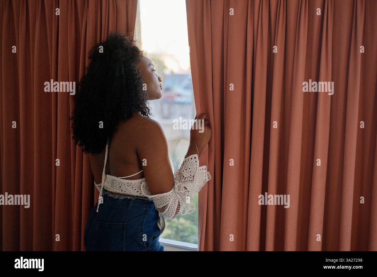 Frau in Spitzenoberteil und Jeans mit pinkfarbenen Vorhängen. Miami, Florida, USA Stockfoto