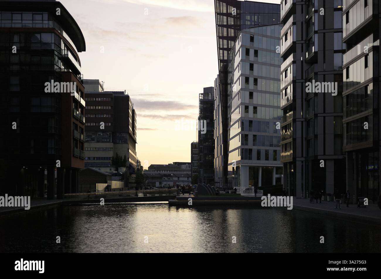 Städtische Skyline in der Abenddämmerung mit modernen Gebäuden und einem Kanal, der das verblassende Licht reflektiert. London, Großbritannien Stockfoto