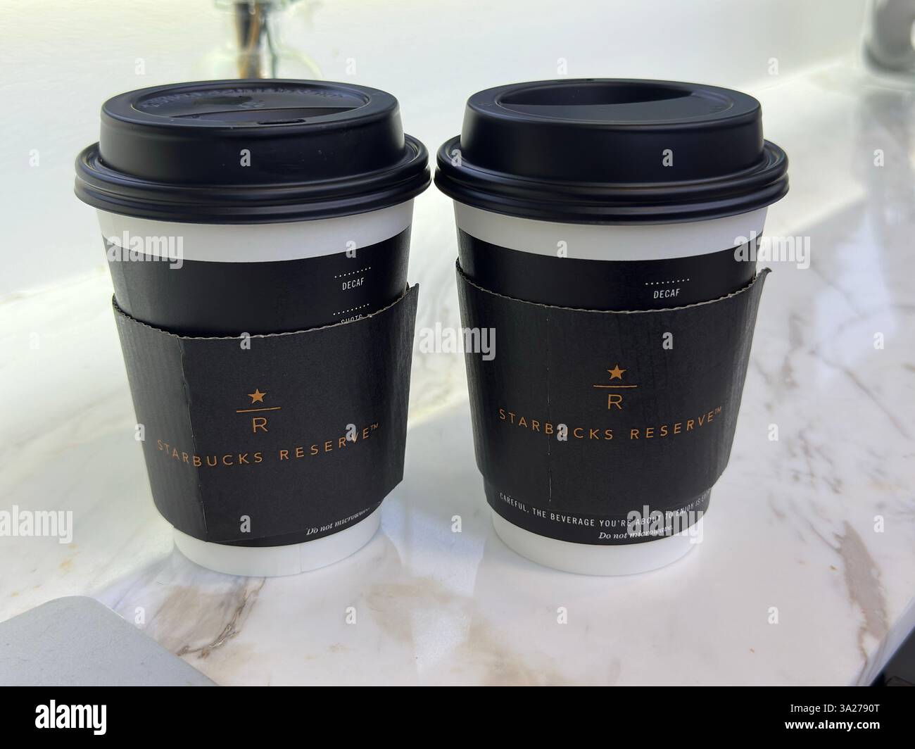 Zwei Starbucks Reserve Kaffeetassen sitzen auf einer weißen Marmoroberfläche, die zum Genießen bereit sind. Stockfoto
