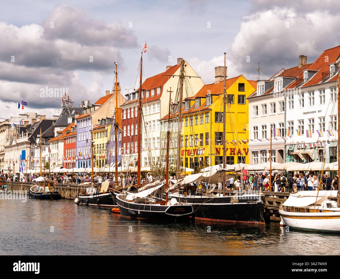 Nyhavn-Kanal mit touristisch überfüllten Ufern, traditionellen Booten und farbenfrohen historischen Stadthäusern während der Hauptsaison, Kopenhagen, Dänemark Stockfoto