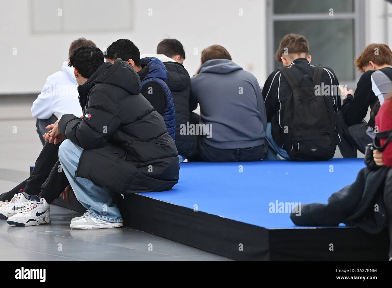 Randmotiv:Jugendliche,Schueler,junger Messebesucher sitzt auf dem Boden und blicken auf ihre Smartphones. Internationale Handwerksmesse IHM München am 12.03.2025 *** Grenzmotiv Junge Menschen, Studenten, junge Messebesucher sitzen auf dem Boden und schauen sich ihre Smartphones an Internationale Handwerksmesse IHM München am 12 03 2025 Stockfoto