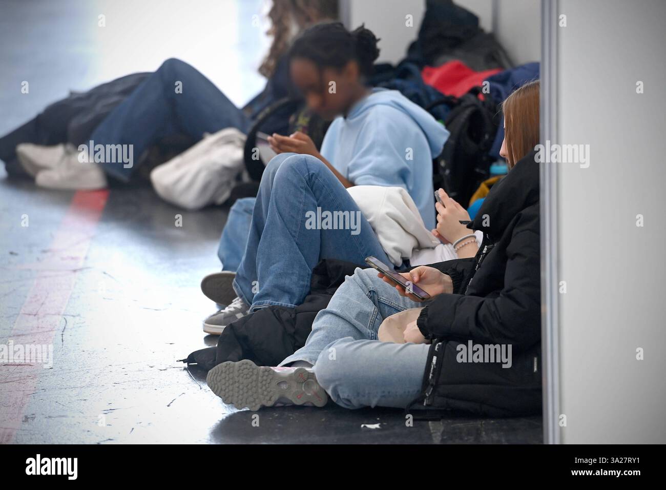 Randmotiv:Jugendliche,Schueler,junger Messebesucher sitzt auf dem Boden und blicken auf ihre Smartphones. Internationale Handwerksmesse IHM München am 12.03.2025 *** Grenzmotiv Junge Menschen, Studenten, junge Messebesucher sitzen auf dem Boden und schauen sich ihre Smartphones an Internationale Handwerksmesse IHM München am 12 03 2025 Stockfoto