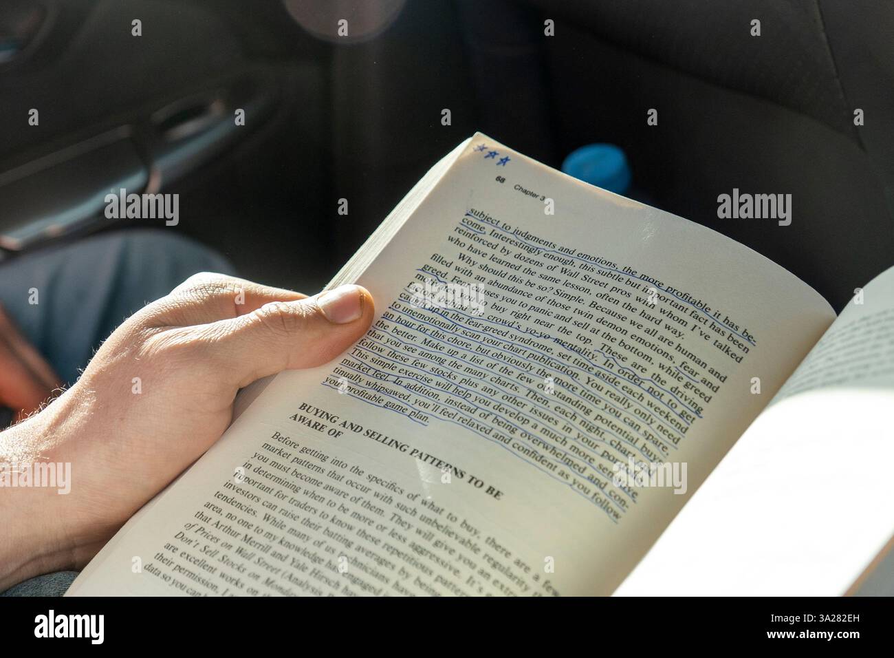 Eine Person sitzt bequem in einem Auto, während sie ein Buch liest Stockfoto
