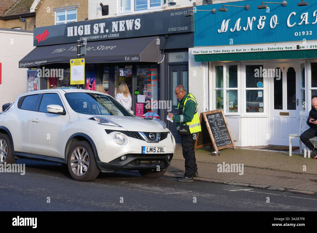 Ein Parkwächter oder Verkehrsaufseher. Eine Strafgebühr für ein Auto, das in einer Vorstadtstraße geparkt ist, Shepperton Surrey England, Großbritannien Stockfoto
