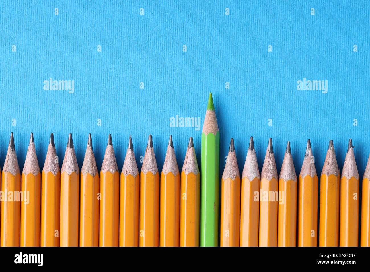 Ein grüner Bleistift unter Graphit auf hellblauem Hintergrund, Draufsicht. Leerzeichen für Text Stockfoto