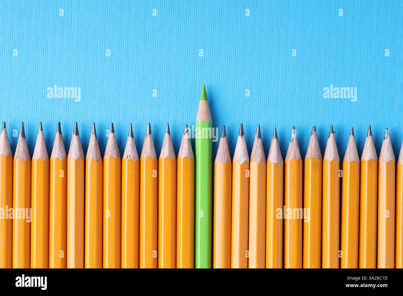 Ein grüner Bleistift unter Graphit auf hellblauem Hintergrund, Draufsicht. Leerzeichen für Text Stockfoto